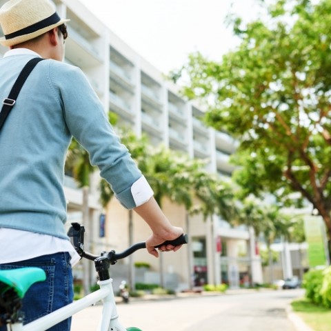 Rear view of student cycling to university in the morning